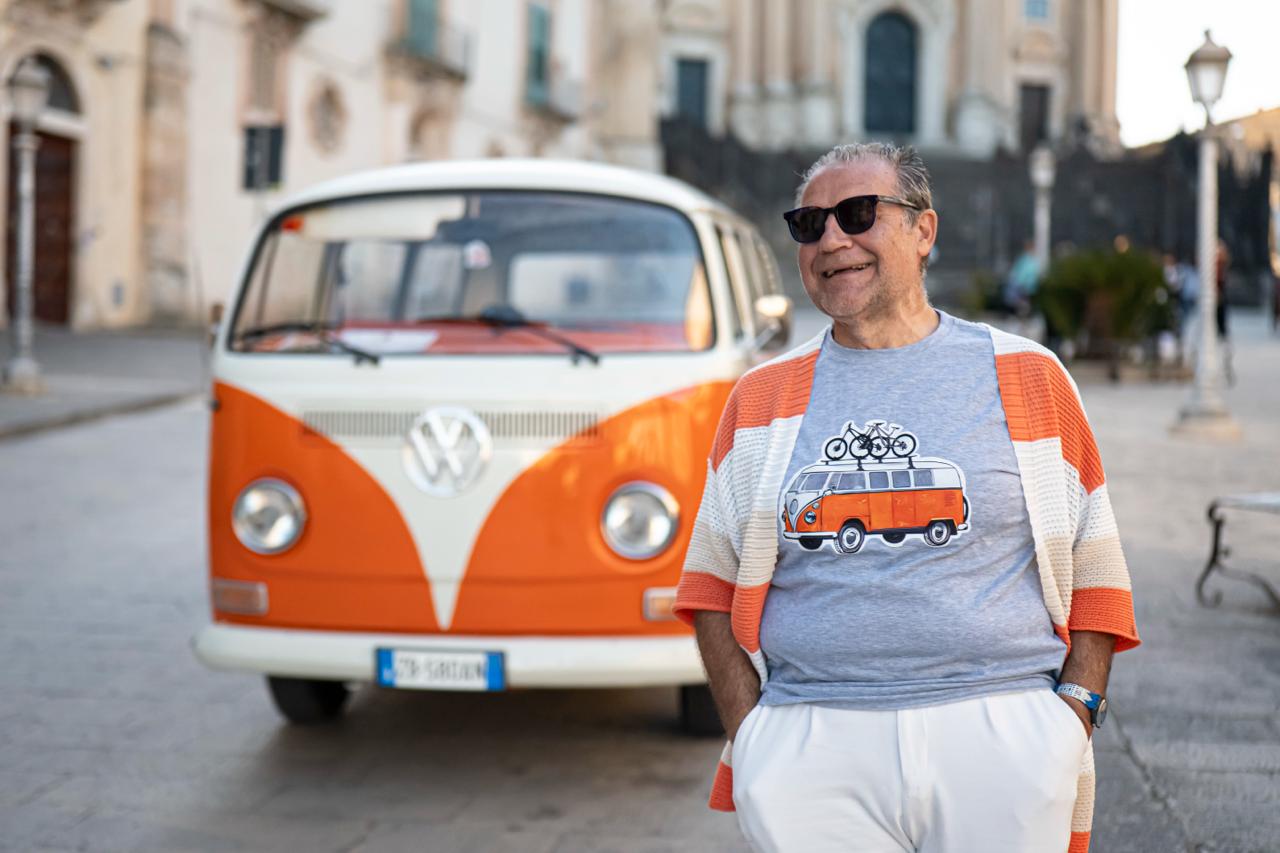 Mario beside his vintage orange VW van in a Sicilian baroque piazza